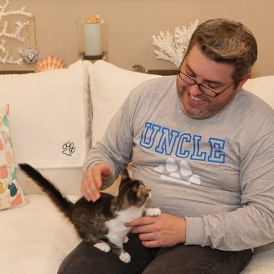 KC cat sitter Zack holding a kitten.